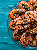 Grilled shrimps served on a dish with olive oil, parsley and garlic over dark green wooden background