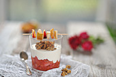 Plum and pear compote in a glass with coconut yoghurt, granola and a fruit skewer (vegan)
