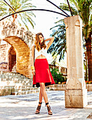 A young woman wearing a white top and a red skirt