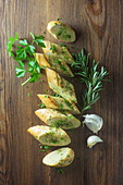 Sliced garlic baguette with herbs on a wooden surface