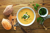 Sweet potato soup with ingredients on a wooden surface