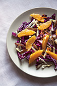 A raw and healthy winter salad ith red cabbage, white cabbage, dates, orange, zest of orange