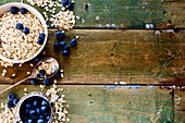 Oatmeal and blueberries in bowls against a rustic wooden background