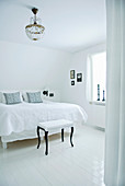 Stool with white upholstery and black legs in white bedroom