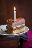 Stück Yellow Cake mit Schokoladenglasur und Kerze