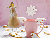 A cup with angel wing cup biscuits and an angel figure
