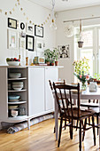 Old chairs with turned spindles and legs in dining room with pale grey sideboard