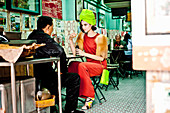 A young woman in an oriental restaurant wearing a neon green turban and a red outfit