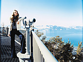 A young woman wearing a cardigan and Marlene jeans on a observation platform