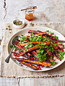 A salad with purple carrots, pomegranate seeds and parsley