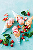Gefrorenes Erdbeer-Sahne-Mousse serviert als Eiskugeln in Eistüten