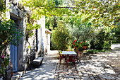 Table and vintage chairs on terrace outside Provençal house