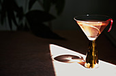 A summer cocktail in a stemmed glass casting a shadow