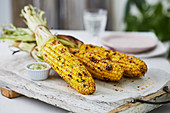 Grilled corn cobs on a wooden board