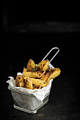 Potato wedges with thyme and Parmesan cheese in a frying basket