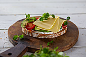 Belegtes Brot mit Käse und Avocado auf Holzschneidebrett (vegan)