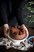 Hände halten Tortenständer mit Schokoladenkuchen