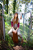 A young woman wearing sitting outside on a suitcase