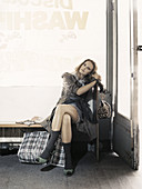 A young woman in a laundromat wearing a trench coat