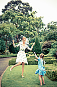 A mother and daughter playing with hula hoops in a garden