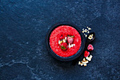 Vintage wooden bowl of tasty berry detox smoothie with frozen berries and oats over dark concrete background