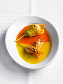 Stuffed zucchini flowers in red and yellow pepper sauce
