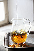 Hot water being added to herbal tea in a glass jug