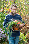 Mann bringt Korb mit frisch geerntetem Gemüse