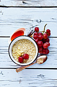 Quinoa flakes, honey, almonds and grapes for healthy breakfast on white wooden background