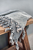 Grey tasselled peshtemal on wooden stool