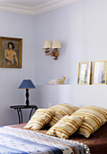 Braun gestreifte Kissen auf dem Bett vor hellblauer Wand mit Sockel