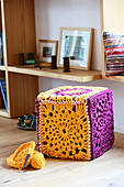 Cubic pouffe with cover made from crocheted granny squares