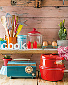 Kitchen utensils, groceries and cacti on wooden shelves