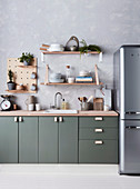Kitchen base cabinet with green front, open shelves above