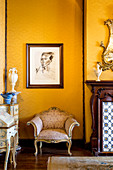 Barocker Sessel unterm Portraitbild an gelber Wand