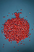 Pomegranate seeds arranged in the shape of a pomegranate on a blue background