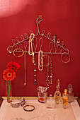 Coat hanger covered in loops of wire used as jewellery rack on red wall