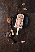 A chocolate ice cream lolly with cocoa powder and cocoa nibs