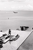 A blonde woman wearing a black bikini by a pool (black-and-white shot)