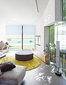 Polsterhocker im modernen Wohnzimmer mit Glaswänden