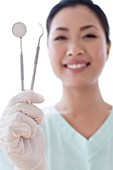 Female dentist holding dental instruments