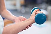 Person using hand weight with support of nurse