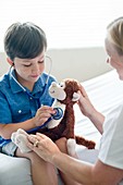 Boy playing with stethoscope and teddy bear