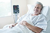 Mature male patient in hospital bed, smiling