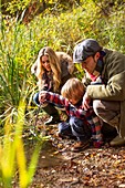 Family crouching by pond