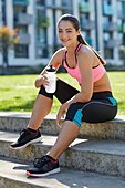 Young woman on steps with water bottle