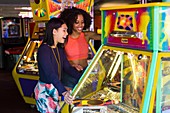 Women playing arcade game at fun fair