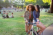 Women in park, one sitting on bicycle