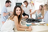 Woman with coffee in kitchen with friends