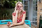 Woman with doughnut covering eye